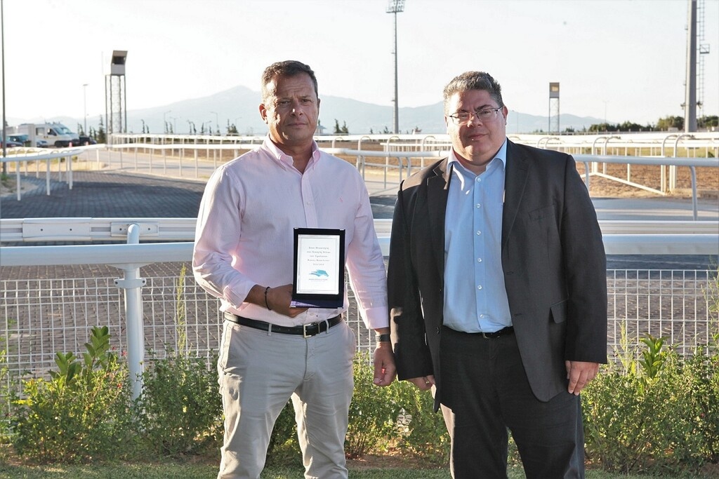 O Chief Operation Officer της ΙΠΠΟΔΡΟΜΙΕΣ Α.Ε.  Κωνσταντίνος Αλεξόπουλος  απονέμει το Τρόπαιο Βάσος Βασιλείου στον Χρήστο Θεοδωράκη, εκπρόσωπο της ιδιοκτησίας  του ίππου ΕΛΕΓΚΑΝΤΛΥ ΜΠΑΟΥΝΤ